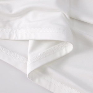 Detailed close-up of white knitted fabric texture and double-stitch sewing of the skirt hem