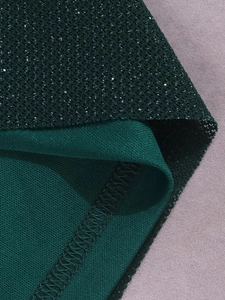 Gros plan du tissu mesh à paillettes vert foncé et de sa doublure douce avec couture