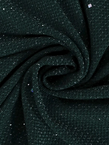 Vue détaillée du tissu en maille vert foncé avec paillettes scintillantes et texture drapée