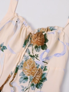 Dettaglio di abito floreale con rose gialle, scollo con volant e lacci sul petto