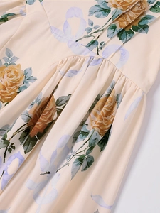 Dettaglio del vestito floreale con rose gialle, fiocchi e vita a pieghe in primo piano