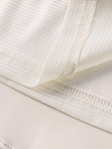 Gros plan détaillé sur la texture côtelée et les coutures soignées de la robe blanc cassé