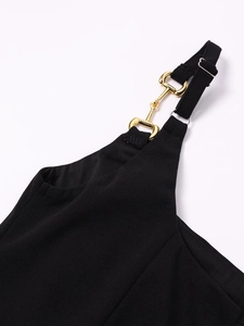 Close-up of golden horsebit hardware on black textured dress shoulder straps