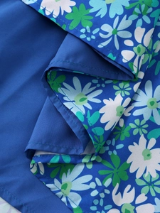Close-up of royal blue floral mini dress featuring detailed daisy prints and hem stitching