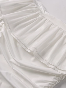 Détail de la robe en organza blanc montrant les volants étagés et le tissu texturé