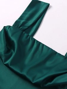Détail de la robe en satin vert foncé avec encolure plissée et texture de soie lisse