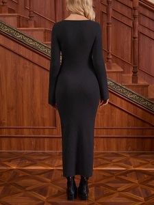 Detailed back view of a slim-fit black ribbed knit midi dress on a wooden staircase