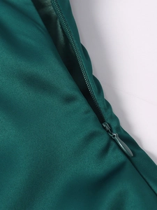 Gros plan sur la fermeture éclair invisible d'une robe longue en satin vert émeraude