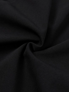 Close-up of black matte textile fabric with fine grain texture and elegant pleats