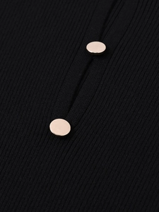 Detail of ribbed knit neckline with polished light gold metal buttons on a black dress