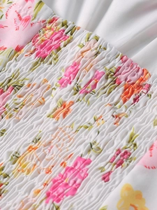 Dettaglio di punto smock floreale su abito estivo con vivaci motivi rosa e arancioni
