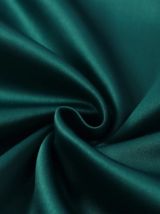 Gros plan macro sur le tissu en satin élastique vert émeraude mat à la texture soyeuse
