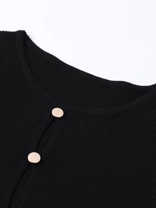 Detail of black ribbed knit dress featuring elegant golden metal buttons on the collar