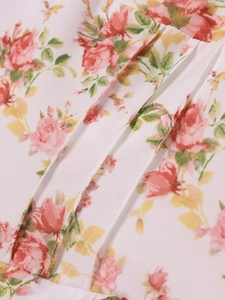 Dettaglio ravvicinato della stampa floreale con rose e della trama a pieghe del vestito