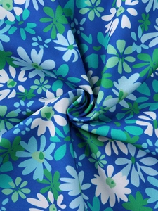 Macro shot of vibrant blue floral dress fabric showing texture and daisy prints