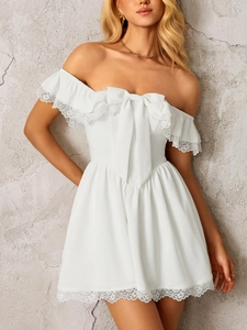 Detail of white off-shoulder dress featuring lace ruffled neckline and large bow accent