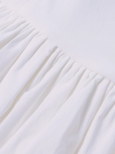Detailed close-up showing textured vertical ruffles and soft white Tencel fabric on the dress