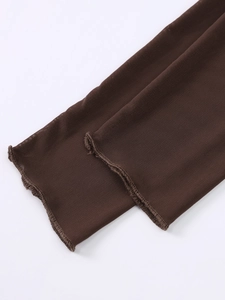 Détail macro du tissu en maille marron foncé et coutures fines sur les manches de robe