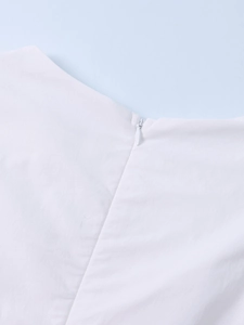 Detail view of the invisible back zipper on a white Tencel dress with smooth fabric texture
