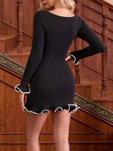 Détail d'une robe en tricot noire avec élégants bords volantés blancs aux poignets et à l'ourlet