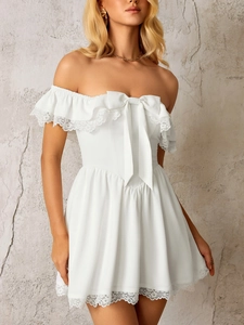 Close-up of white off-shoulder mini dress with lace trim and large bow detail