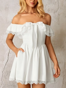 Detailed view of white off-shoulder lace dress with bow decoration and side pockets