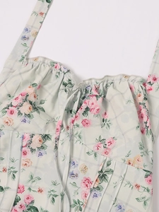 Dettaglio abito a fiori con scollo a balze e stampa a quadretti verdi su tessuto