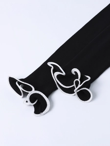 Détail de manches en maille noire avec bords à volants contrastés blancs et revers