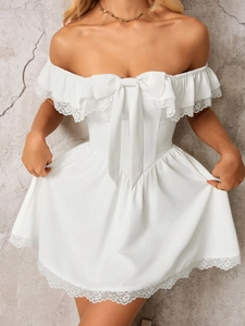 Detail of white off-shoulder mini dress featuring a large bow and delicate lace trim