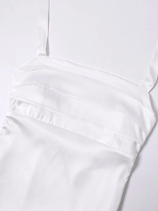 Detailed view of white satin dress with fine horizontal pleats and thin shoulder straps