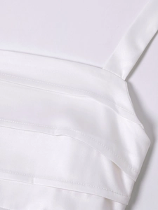 Detail of white satin dress showing smooth fabric texture and delicate spaghetti straps