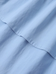 Macro shot of light blue tencel fabric showing fine vertical texture and layered seams