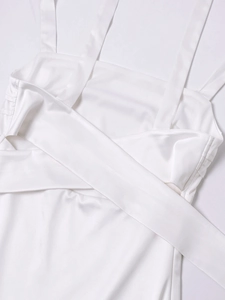 Close-up of white satin dress detailing silky fabric texture and thin strap stitching