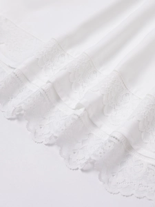Detailed macro view of white floral lace trim on a silky summer A-line mini dress