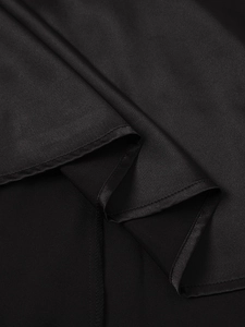 Close-up of black matte satin dress showing smooth fabric texture and fine hem stitching