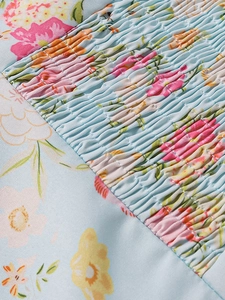 Dettaglio del tessuto a fiori con arricciatura elastica su un abito estivo a trapezio
