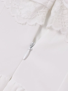 Detailed view of the invisible teardrop zipper and delicate floral lace on a white dress