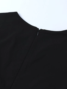 Detail view of the invisible back zipper and round neckline on a black Tencel dress