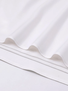 Detail shot of white satin mini dress featuring neat double-stitched hem and smooth texture
