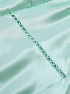 Detail of mint green matte satin dress featuring intricate cross-stitched lace embroidery