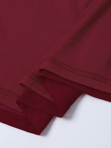 Détail macro d'une robe en maille bordeaux montrant des doubles coutures et une texture fine