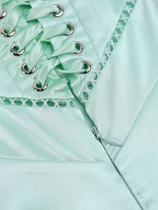 Close-up of mint green satin dress with cross lacing and delicate lace trim detail