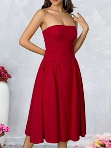 Detail view of the elegant ruched waist and strapless bodice of this red midi dress
