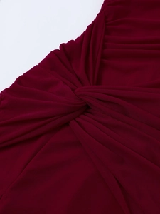 Détail macro d'une robe en tulle bordeaux avec un nœud central et des plis élégants