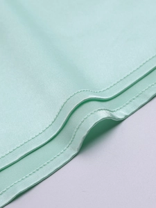 Close-up of mint green matte satin fabric showing high-quality stitching and texture