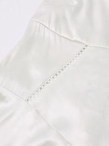 Macro detail of ivory matte satin dress showing elegant hollow-out X-shaped braided stitching