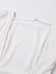 Detail of white seersucker summer dress with adjustable straps and textured fabric surface