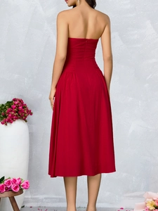 Detail of deep red backless dress showing pleats on the waist and a flared midi skirt