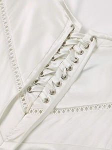 Detail of matte satin dress featuring lace-up metal eyelets and geometric embroidery
