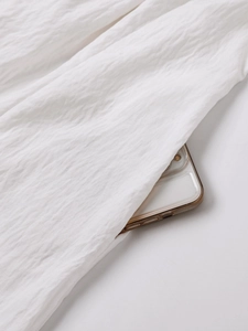 Detail of a functional side pocket on a white backless dress with textured cotton fabric